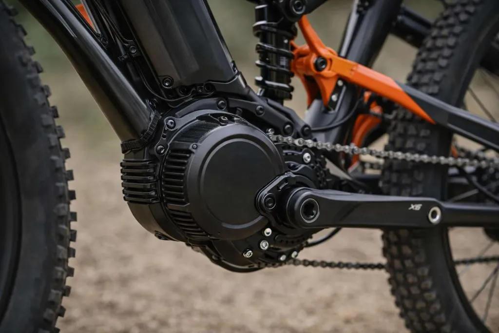Close-up of a mid-drive e-bike motor at the cranks with chain and suspension linkage