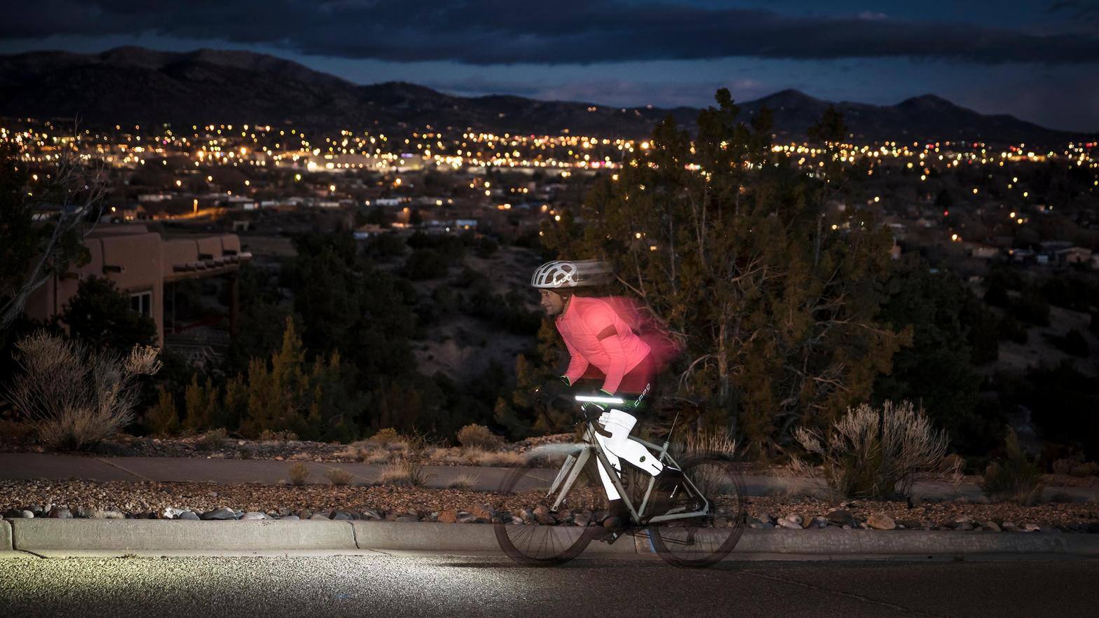Cyclist commuting on a city street at night with a bright headlight cone