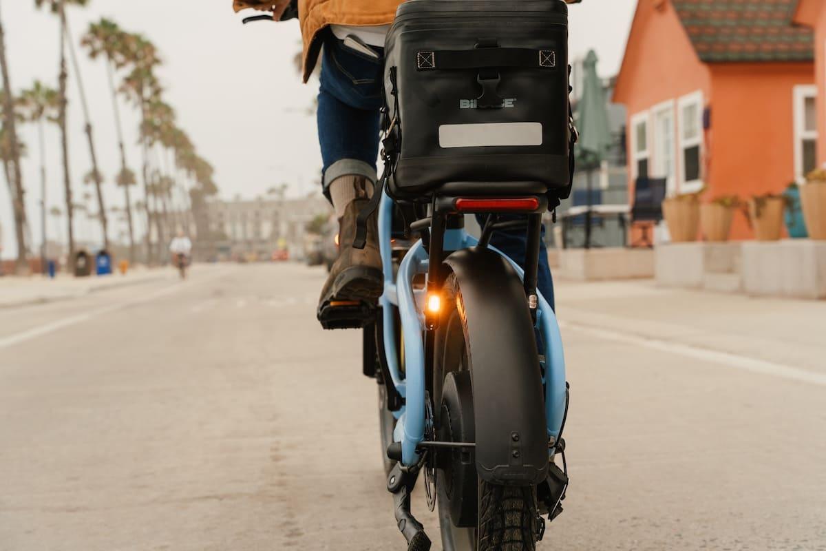 Rider on a Segway Muxi Pro on a paved park path with cargo on the rear rack