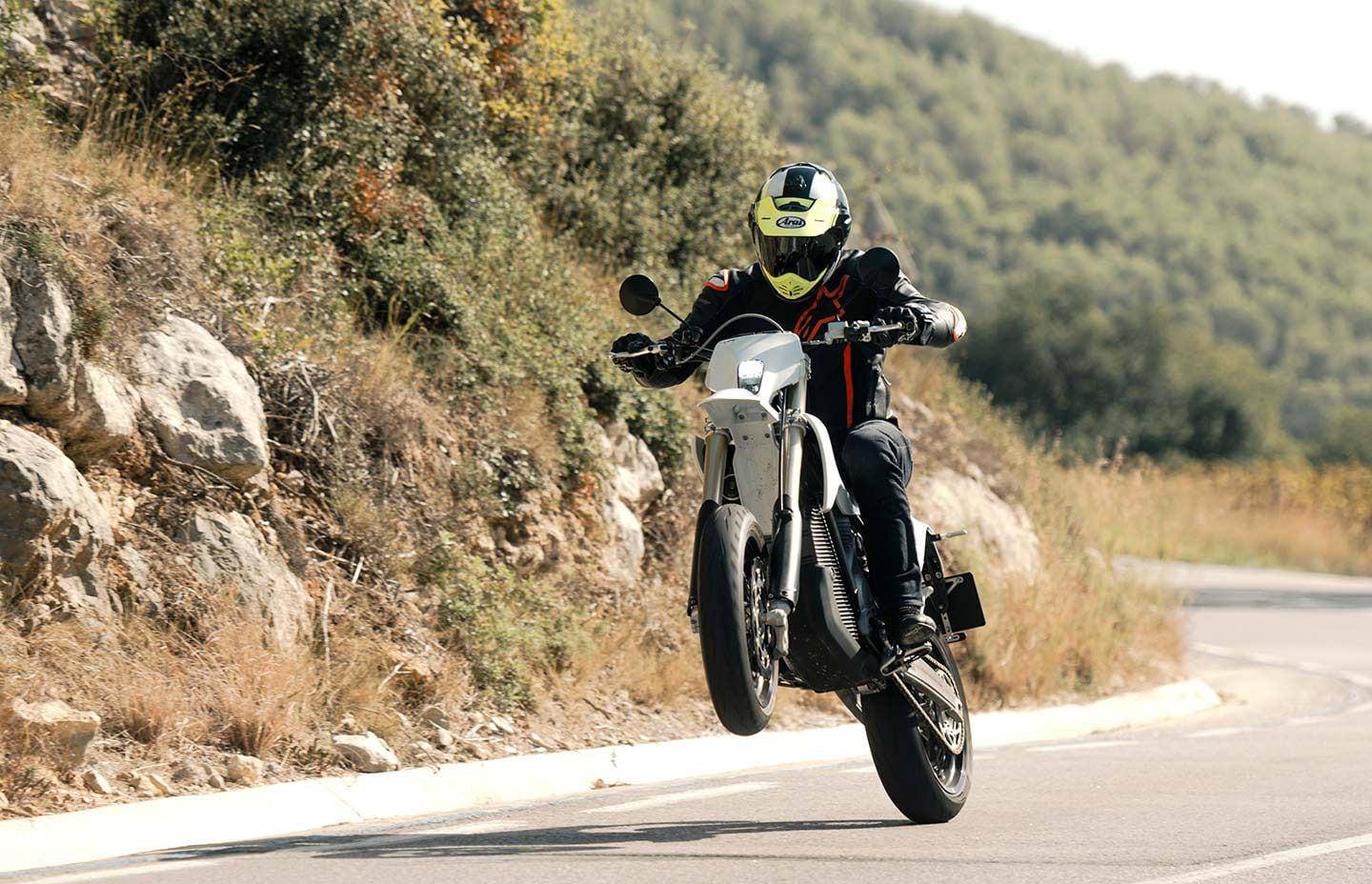 Rider on a Stark Varg SM supermoto pulling a wheelie on a mountain road near Barcelona